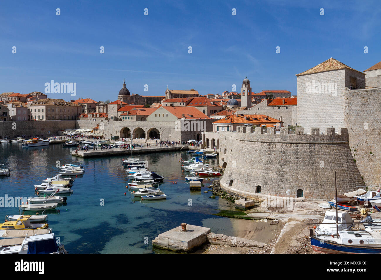 Tetto dalle tegole rosse e blu chiaro acqua del vecchio porto della città e le antiche mura del centro storico della città di Dubrovnik, Croazia. Foto Stock