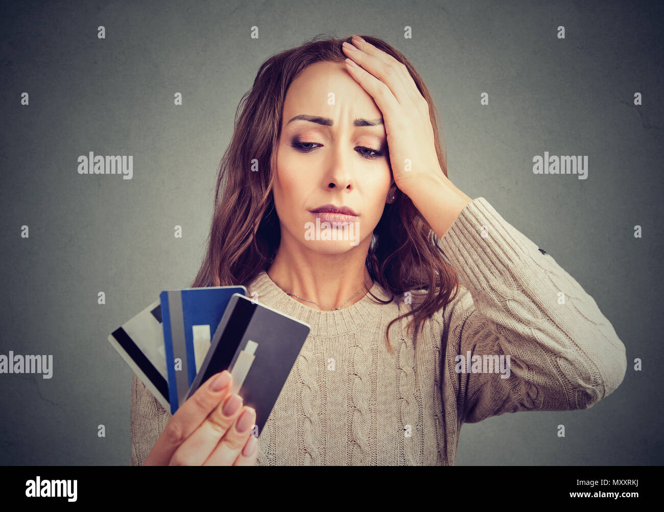 Giovane donna tenendo le carte di credito e alla ricerca ha sottolineato aventi problemi finanziari. Foto Stock