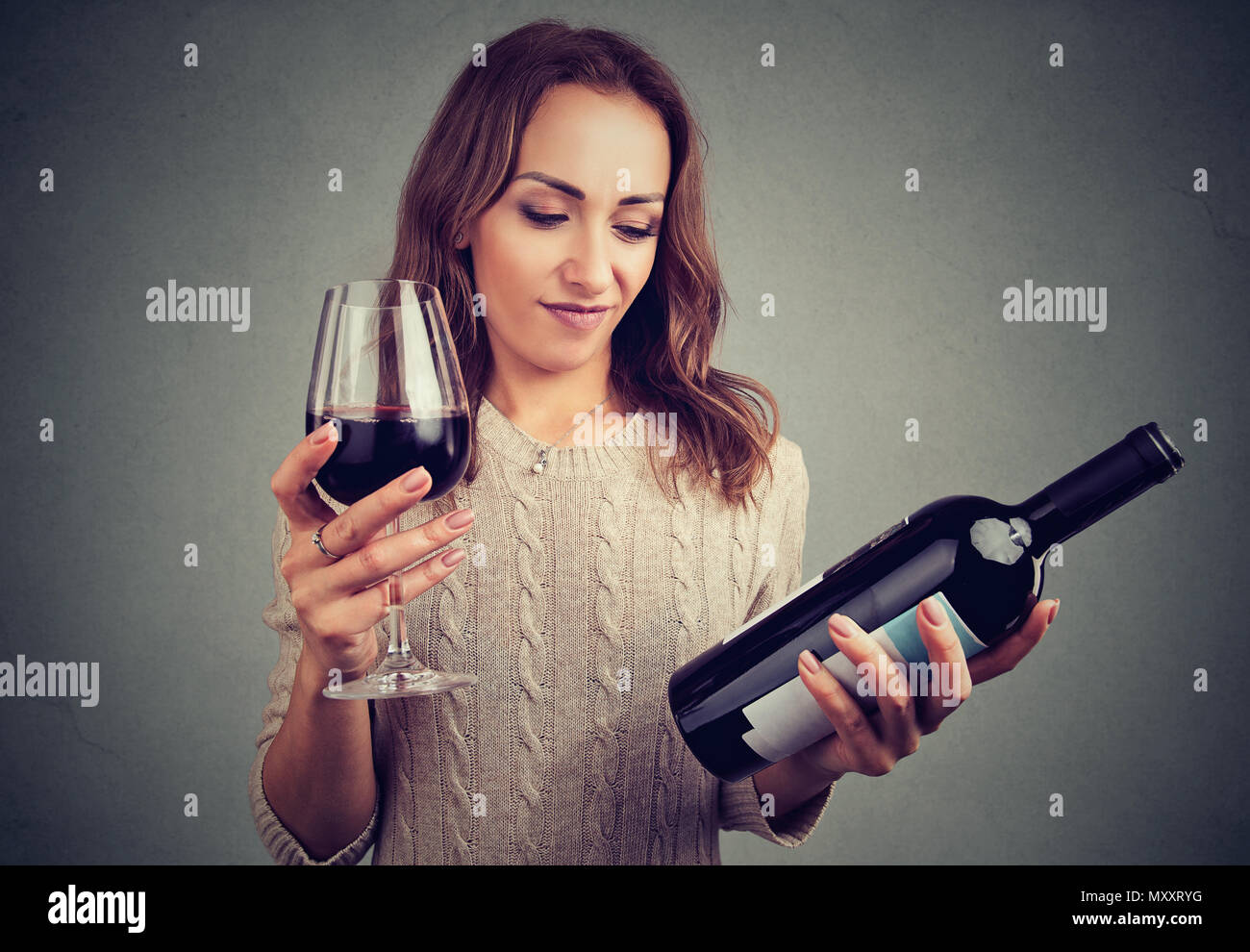Ragazza giovane con la bottiglia e bicchiere di vino rosso cercando scontroso a causa del cattivo gusto Foto Stock