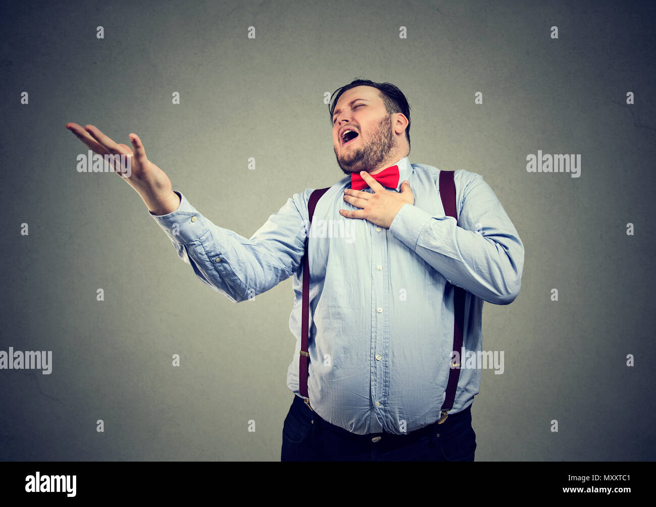 Giovane uomo paffuto urlando in sentimenti di cuore spezzato alla ricerca disperata durante la riproduzione di un dramma scena Foto Stock