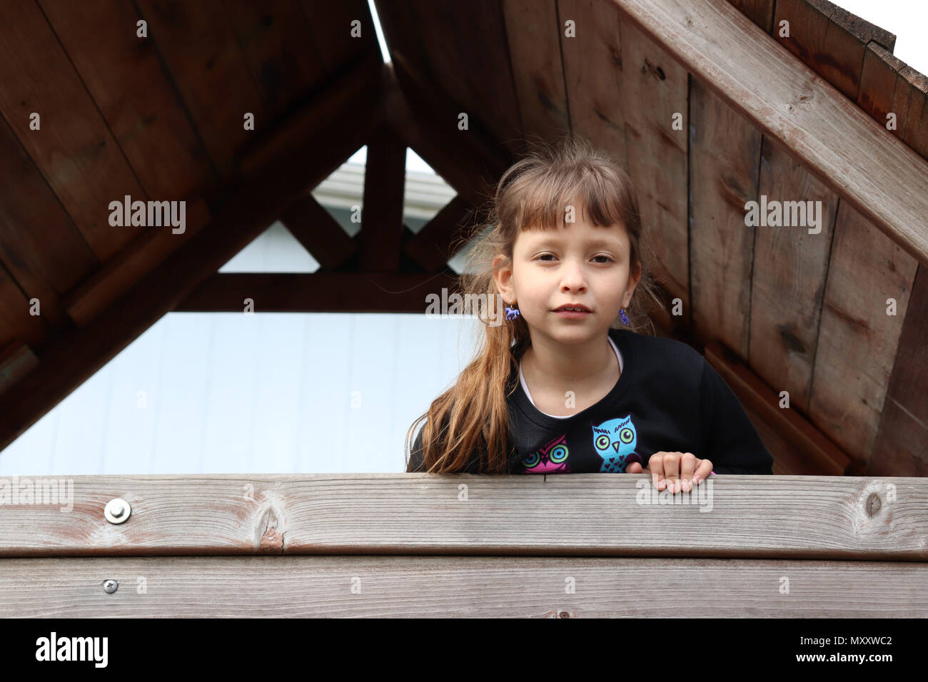 Bambina in piedi nella sua clubhouse in legno Foto Stock