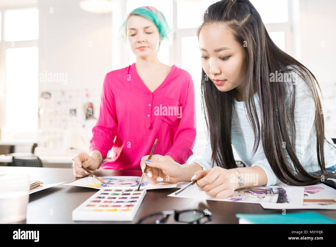 Ritratto di contemporaneo di due giovani donne schizzi di disegno con acquerelli su creative design project nel piccolo atelier studio, concentrarsi sui giovani asiatici w Foto Stock