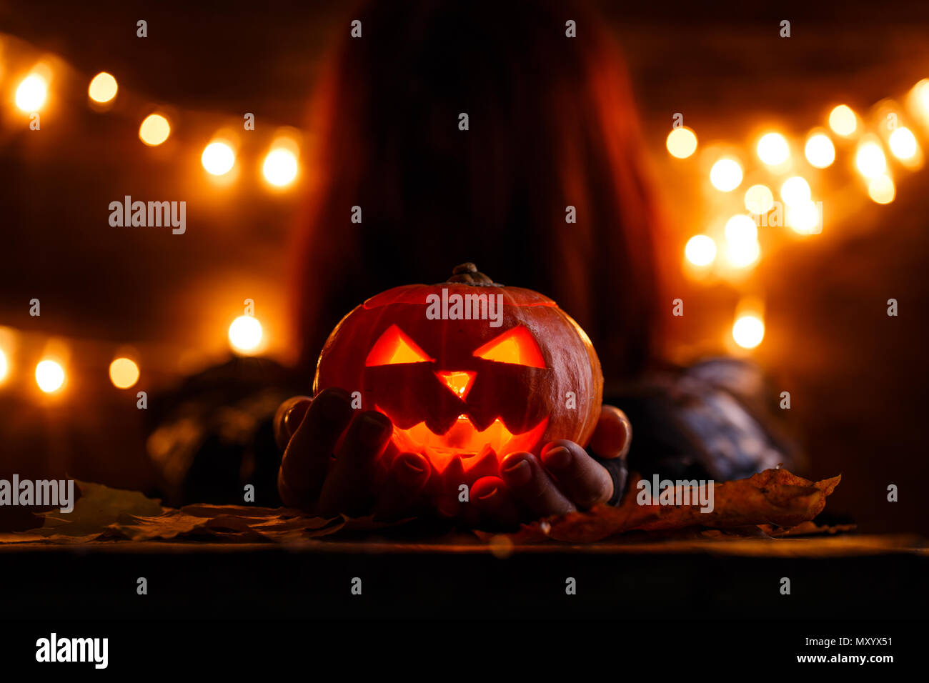 Foto di strega con capelli lunghi tenendo la zucca di Halloween Foto Stock