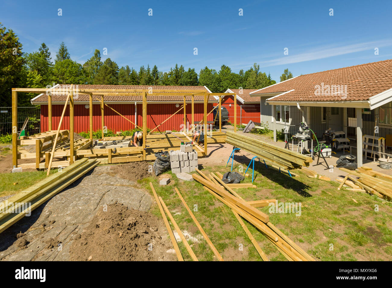 Falegnami per lavorare in esterno a erigere un grande patio con pergola e round firepit Foto Stock