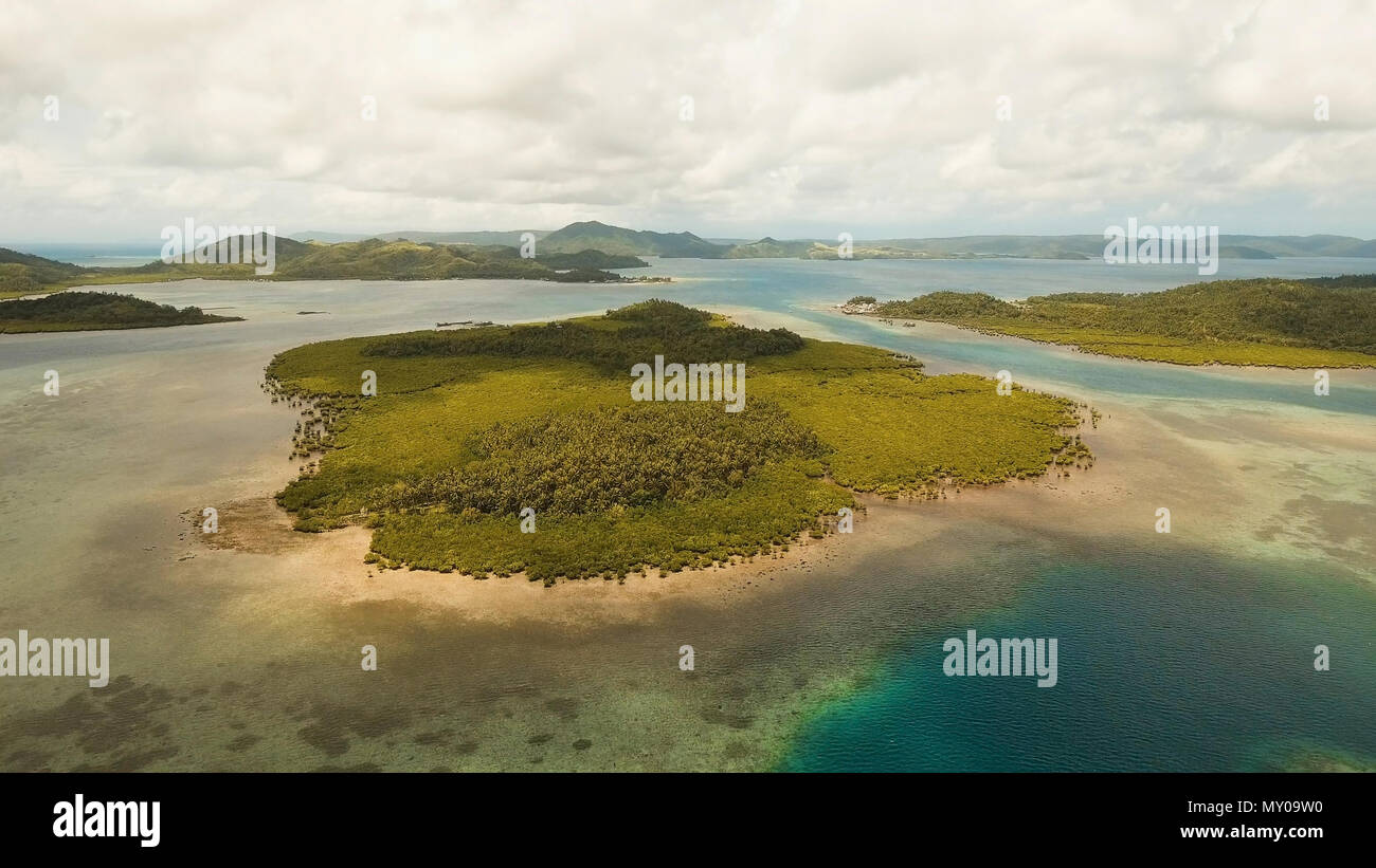 Vista aerea: spiaggia, isola tropicale, Baia Mare e laguna, Siargao. Paesaggio tropicale hill, nuvole e montagne rocce con la foresta pluviale. Acque azzurre della laguna. Paesaggio Shore Bay. Seascape. Concetto di viaggio. Foto Stock