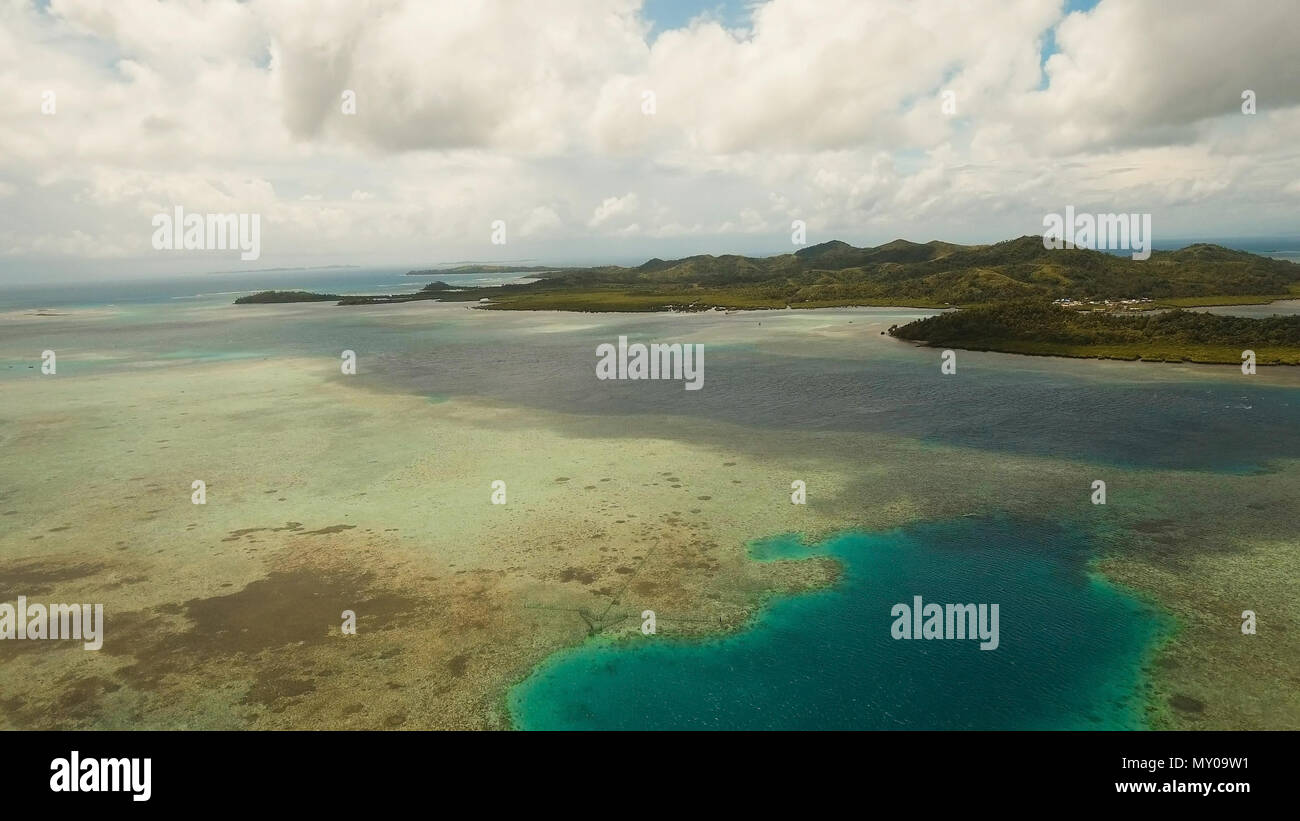 Vista aerea: spiaggia, isola tropicale, Baia Mare e laguna, Siargao. Paesaggio tropicale hill, nuvole e montagne rocce con la foresta pluviale. Acque azzurre della laguna. Paesaggio Shore Bay. Seascape. Concetto di viaggio. Foto Stock