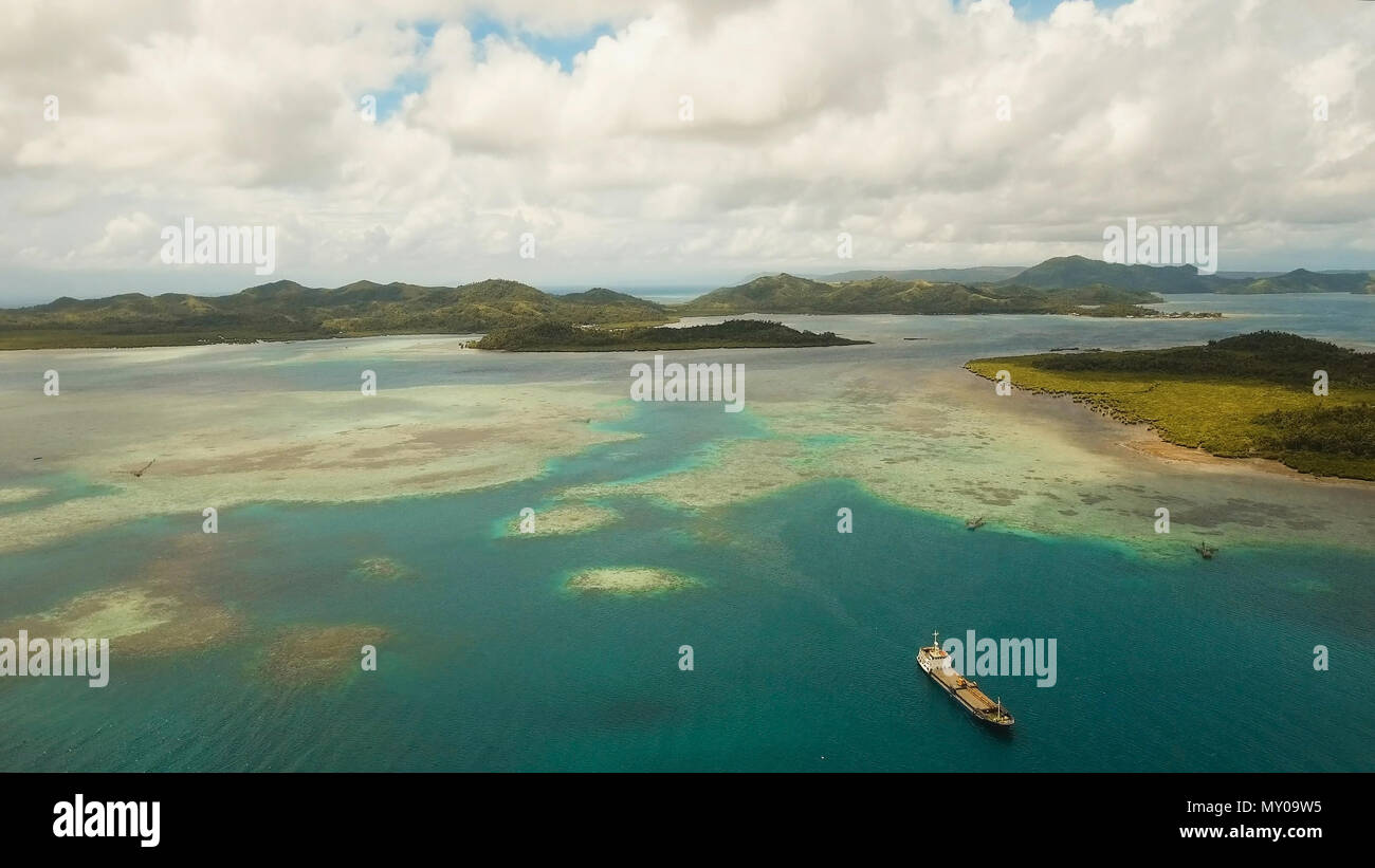 Vista aerea: spiaggia, isola tropicale, Baia Mare e laguna, Siargao. Paesaggio tropicale hill, nuvole e montagne rocce con la foresta pluviale. Acque azzurre della laguna. Paesaggio Shore Bay. Seascape. Concetto di viaggio. Foto Stock