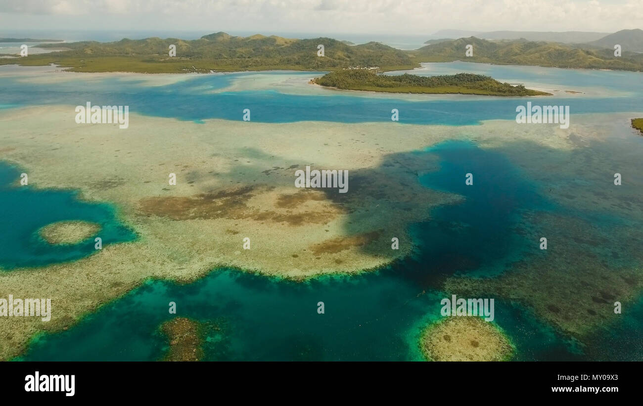 Vista aerea: spiaggia, isola tropicale, Baia Mare e laguna, Siargao. Paesaggio tropicale hill, nuvole e montagne rocce con la foresta pluviale. Acque azzurre della laguna. Paesaggio Shore Bay. Seascape. Concetto di viaggio. Foto Stock