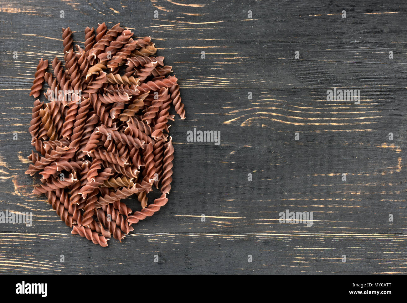 Piccolo pelo scuro di pasta fusilli su un vuoto sullo sfondo di legno Foto Stock