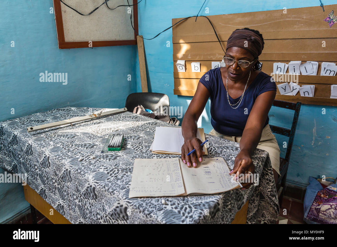 Insegnante compiti di classificazione nella sua aula nella comunità di Pepito Tey, Cuba Foto Stock