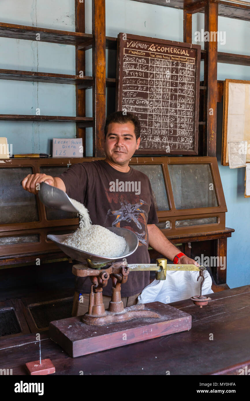 Uomo fuori misura razioni di riso presso il governo negozio di approvvigionamento nella Comunità di Pepito Tey, Cuba Foto Stock