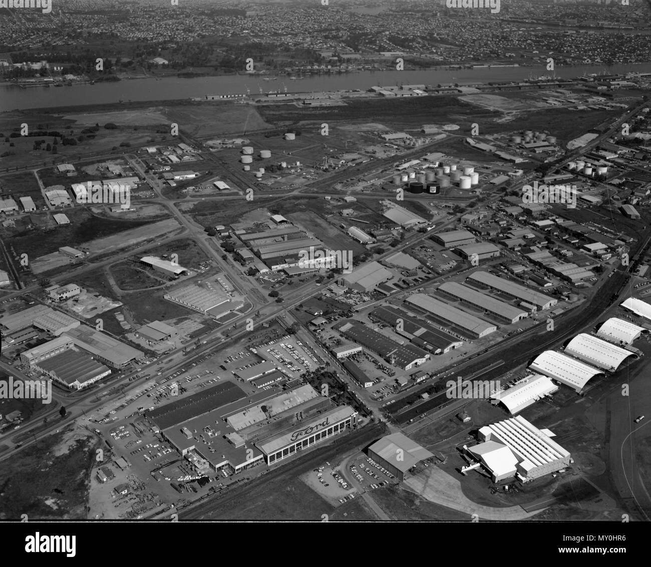 Ford Motor Factory, Eagle Farm, Brisbane, 1967. La Ford Motor Company of Australia, una società controllata di Ford in Canada, stabilito un autoveicolo impianto di assemblaggio ad Eagle Farm nel 1926. Il sito era pronto accesso al trasporto su strada e ferrovia, e servizi di spedizione sul fiume. La fabbrica ha svolto un importante ruolo di fabbricazione durante la Seconda Guerra Mondiale la costruzione di una gamma di prodotti e parti di ricambio per le forze militari di entrambi in Australia e negli Stati Uniti. La fabbrica chiuse nel 1998. In basso a destra è la vecchia fattoria Eagle aeroporto e in background è Hamilton wharf sul Fiume Brisbane. Foto Stock