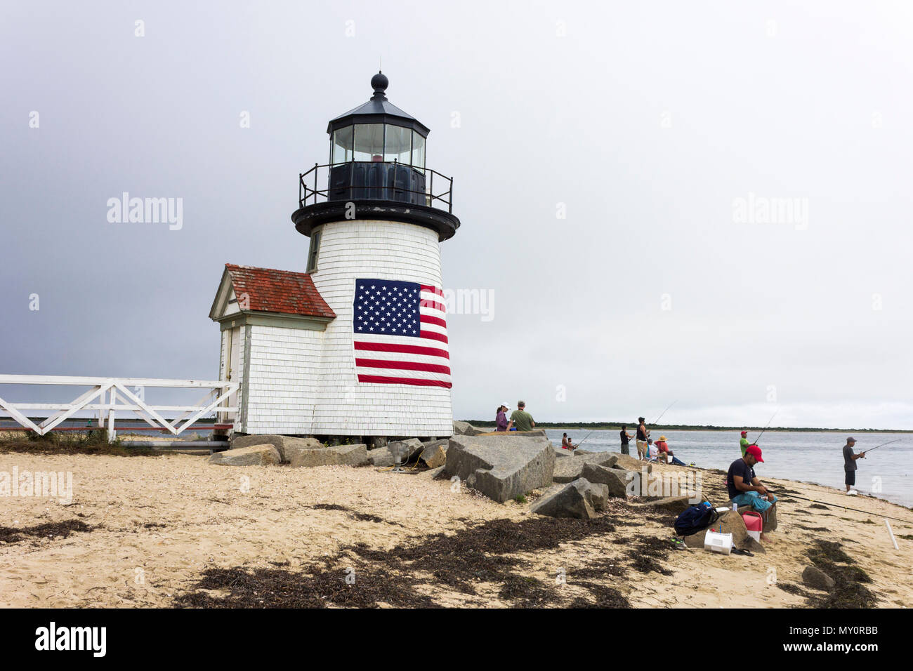 Nantucket, Massachusetts. Brant punto luce, un faro situato sul porto di Nantucket Island, con diverse persone di pesca e una bandiera americana Foto Stock