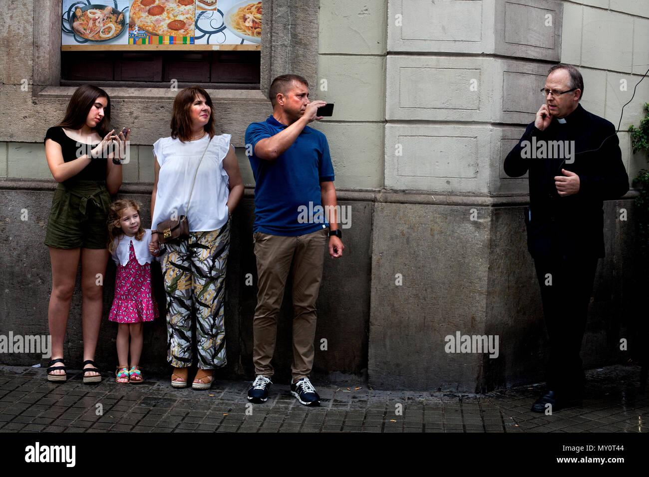 Famiglia di turisti per guardare e registrare una comunione processione su un umido domenica a Barcellona, Spagna. Foto Stock