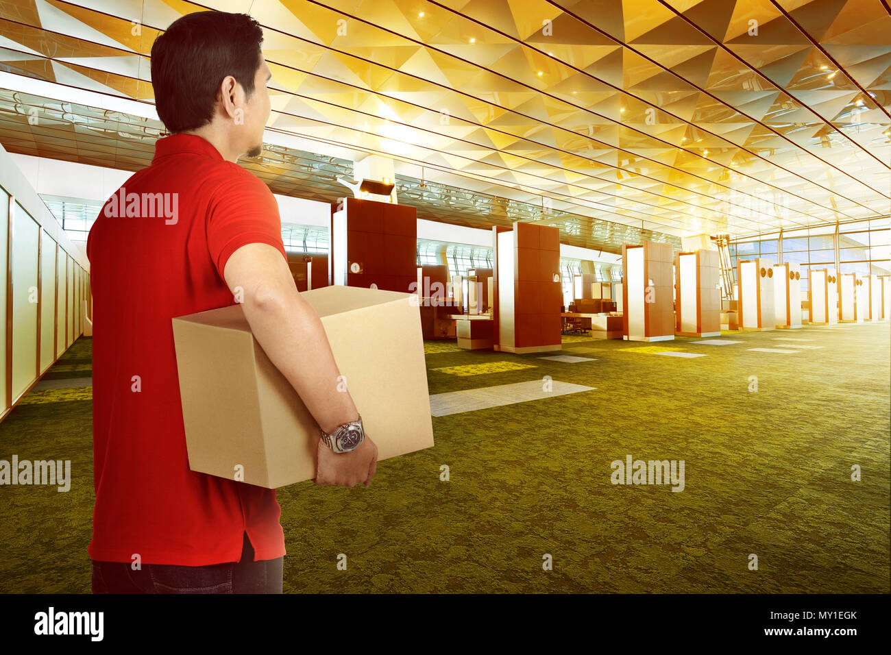 Attraente consegna asiatici uomo portare il pacchetto a consegnare su edificio moderno Foto Stock
