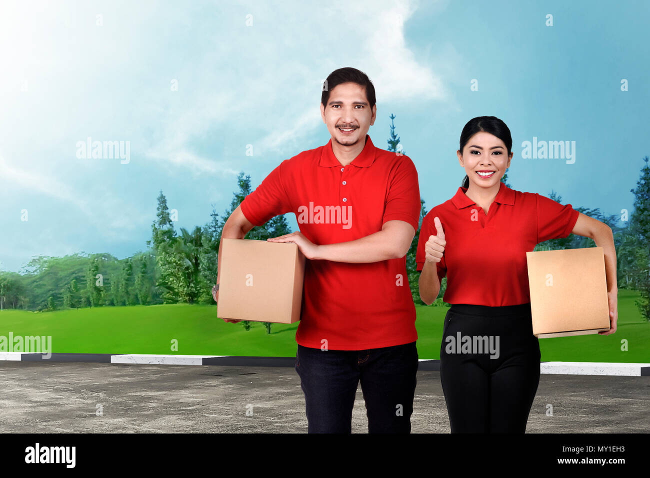 Sorridente asian delivery service team con il pacchetto sulla strada Foto Stock