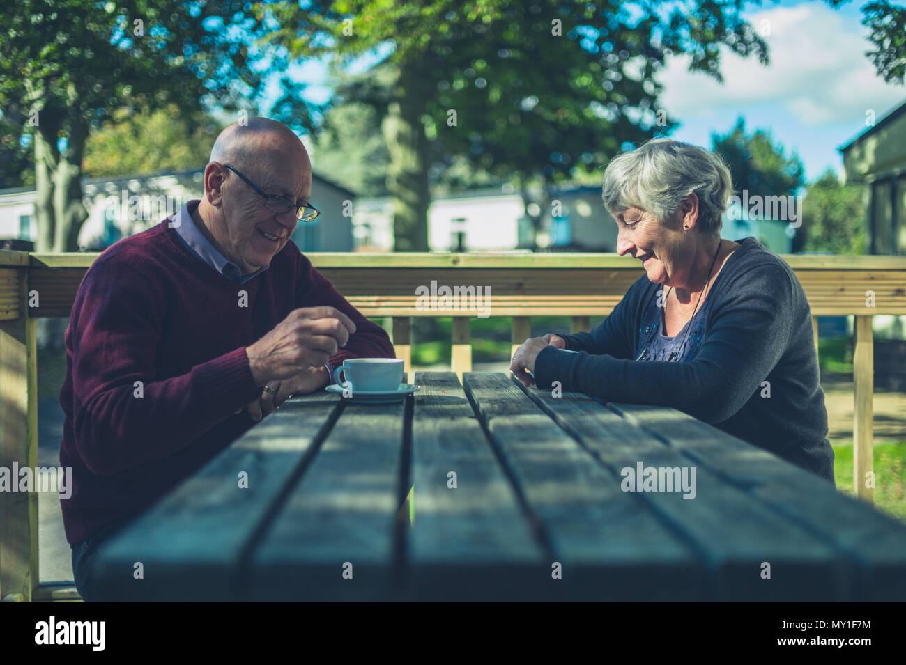 Una coppia senior sono seduti ad un tavolo in un caravan park e vengono a bere caffè Foto Stock