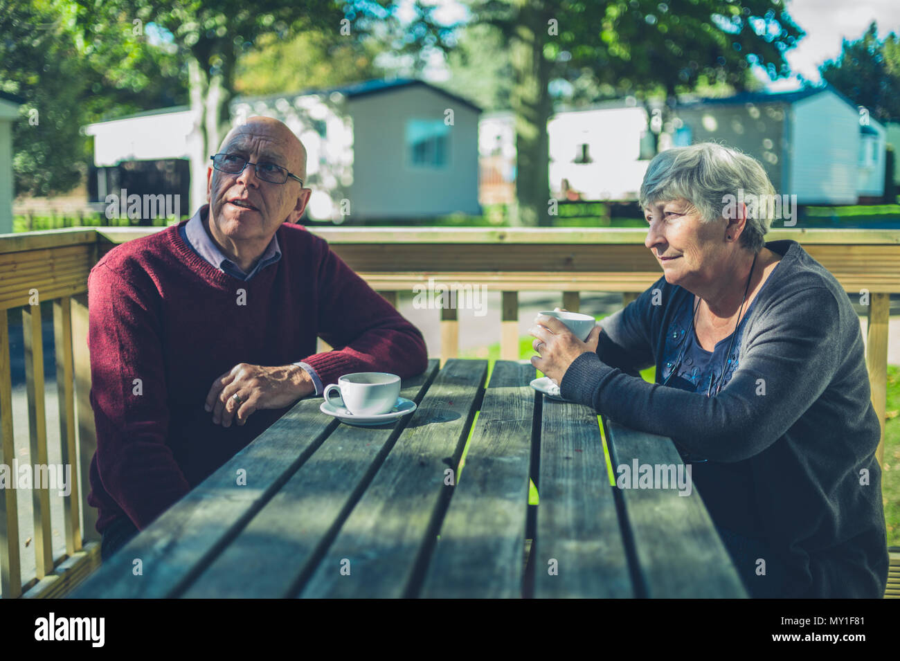 Una coppia senior sono seduti ad un tavolo in un caravan park e vengono a bere caffè Foto Stock