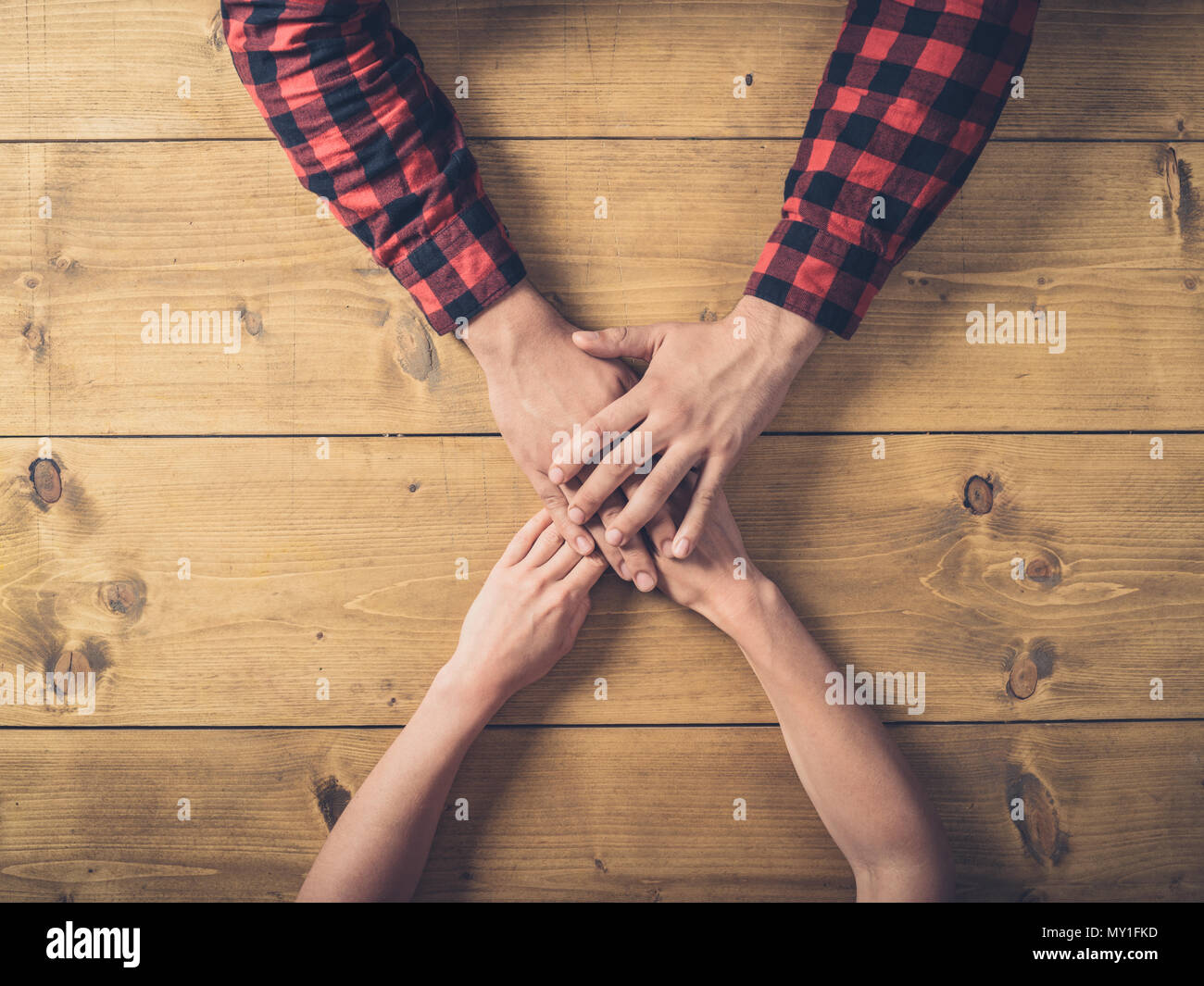 Tettuccio di colpo di un giovane uomo e donna tenendo le mani su una tavola di legno Foto Stock