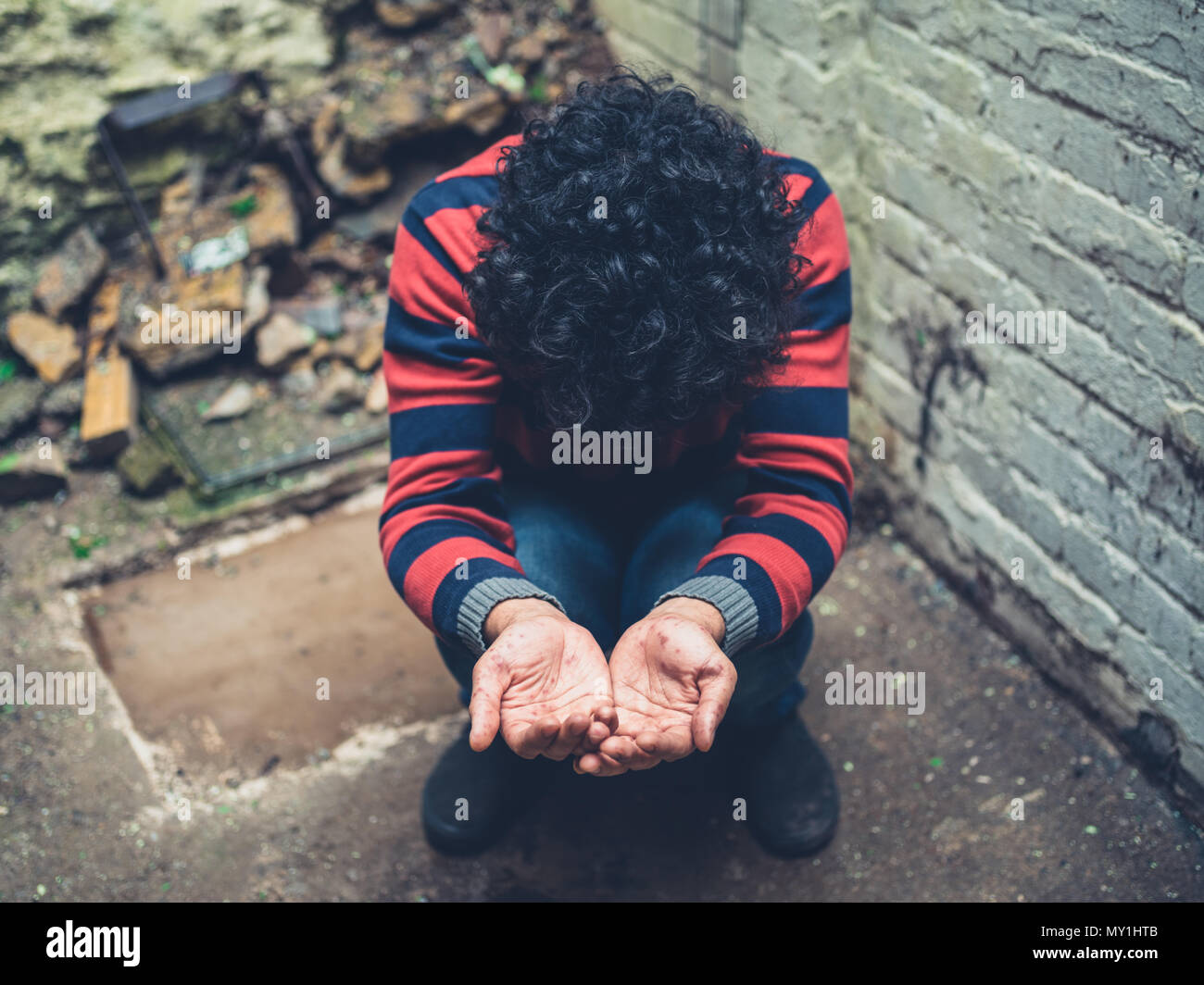 Un giovane uomo con una eruzione cutanea sulle sue mani è a mendicare al di fuori Foto Stock