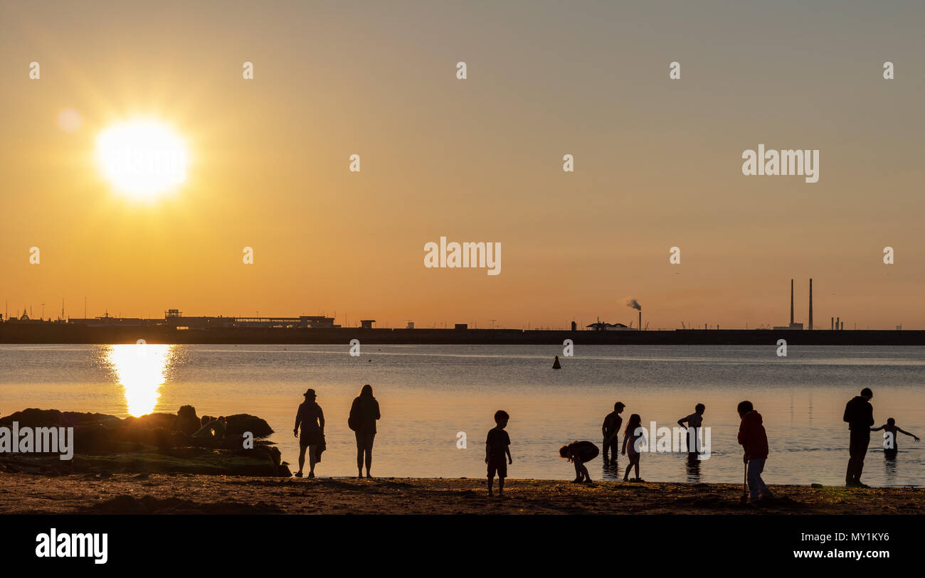 Persone casualmente in piedi al tramonto su una spiaggia. Foto Stock
