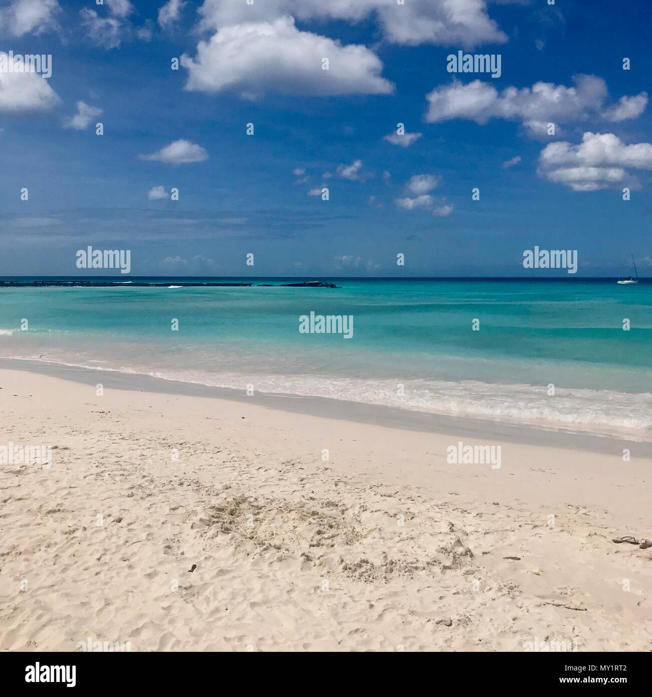 Idilliaco e bel pomeriggio in spiaggia in Barbados (isola dei Caraibi): Nessuno, di sabbia bianca e limpide acque turchesi con le onde e una soleggiata cielo blu Foto Stock