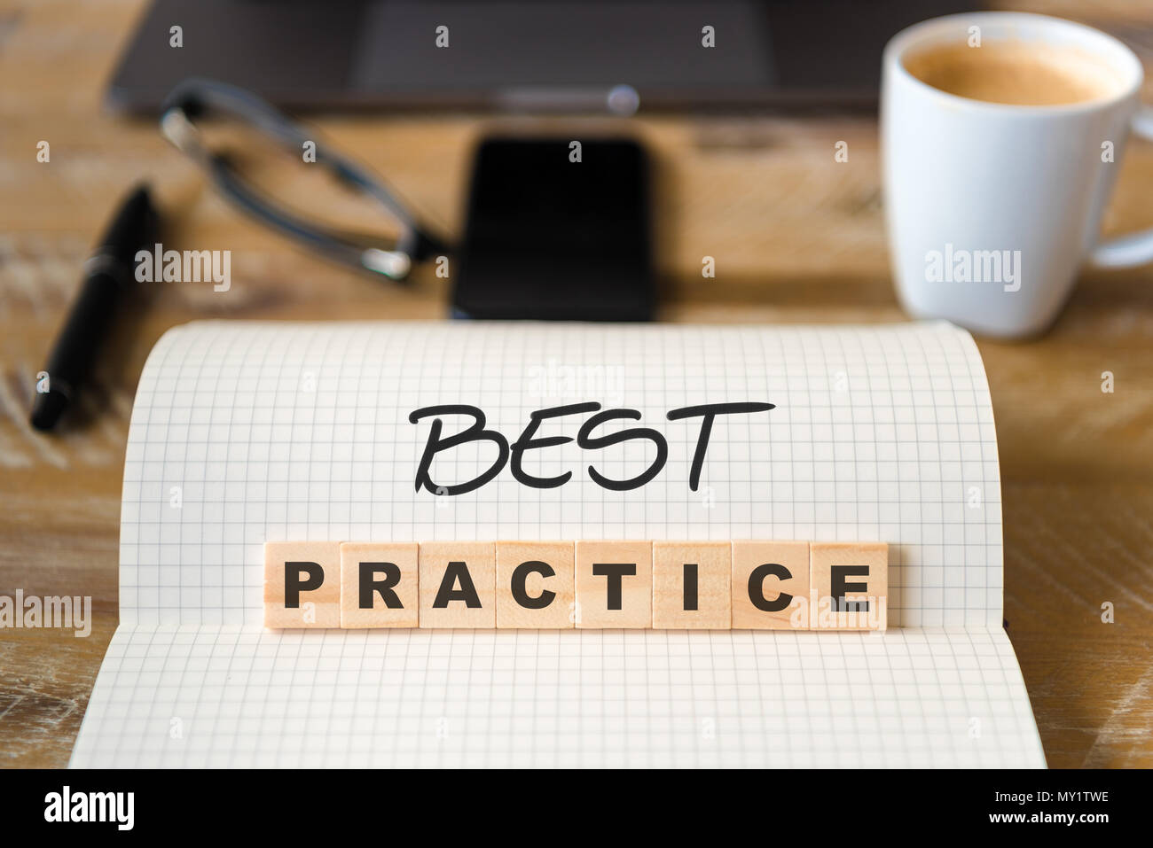 Primo piano su notebook su tavola di legno sfondo, concentrarsi sui blocchi di legno con lettere che le migliori pratiche di testo. Foto Stock
