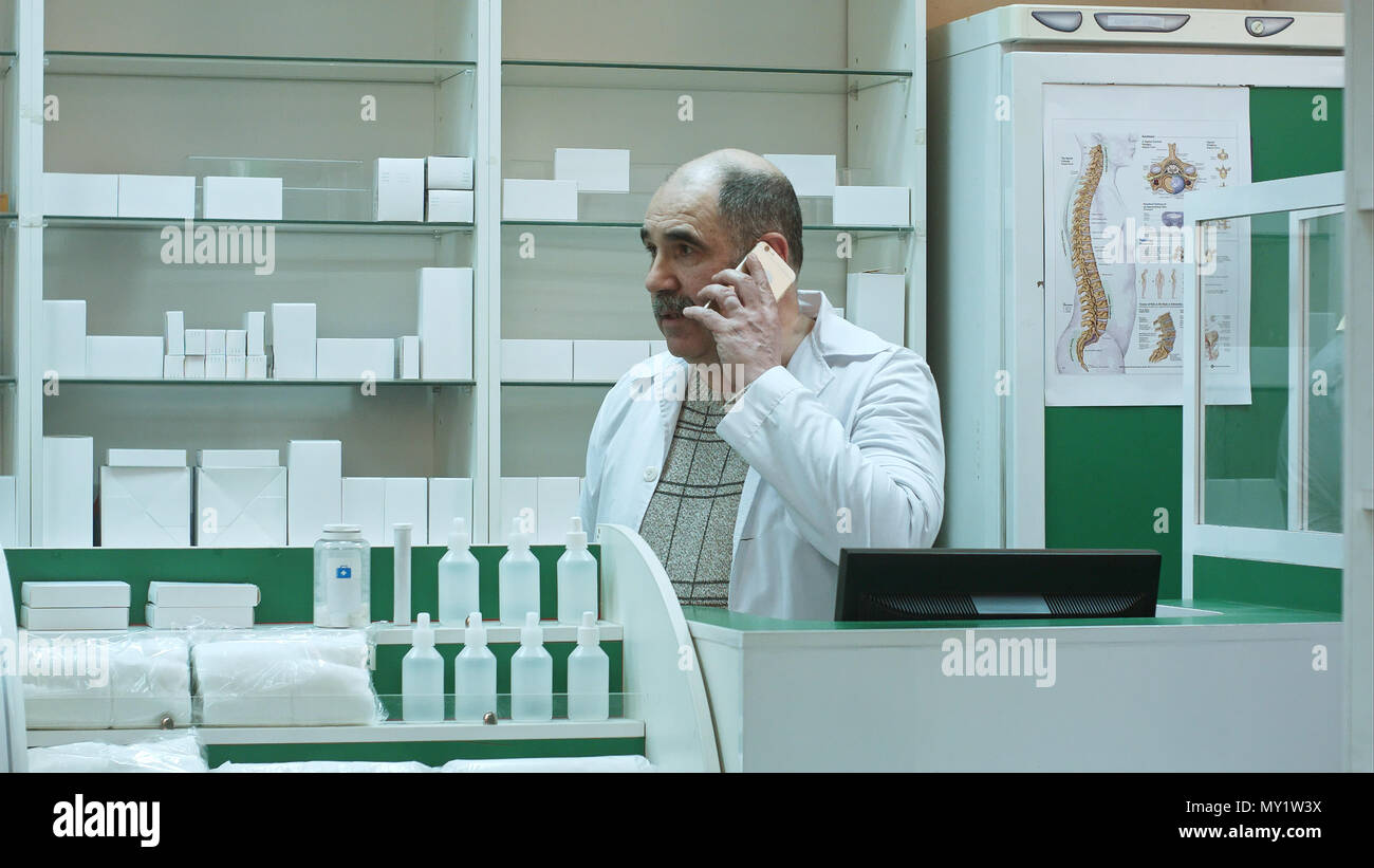 Il farmacista consulting cliente via telefono cellulare in drug store Foto Stock