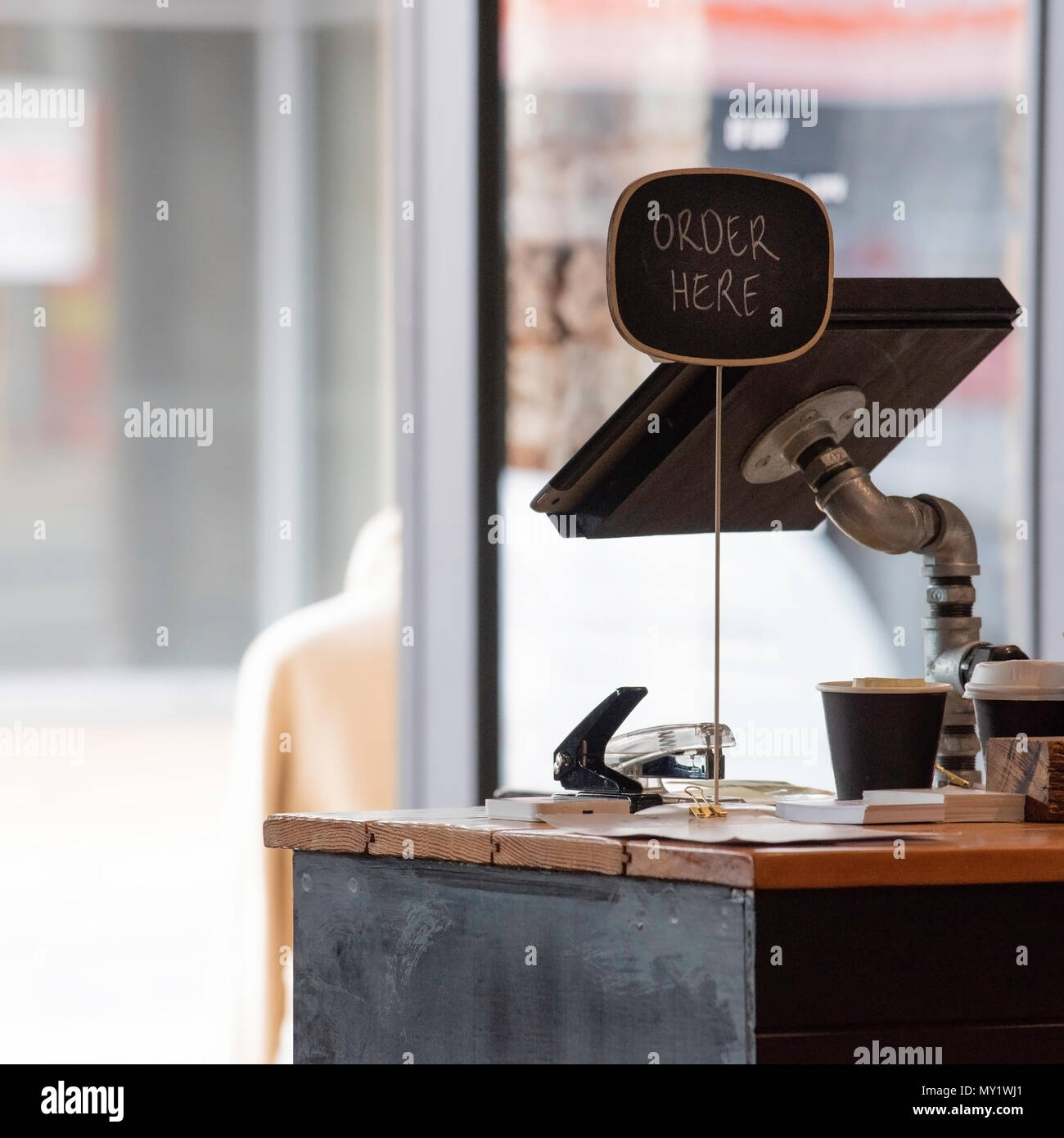 Un retail moderno coffee shop bancone di vendita con un ordine qui segno e un computer per il terminale Foto Stock