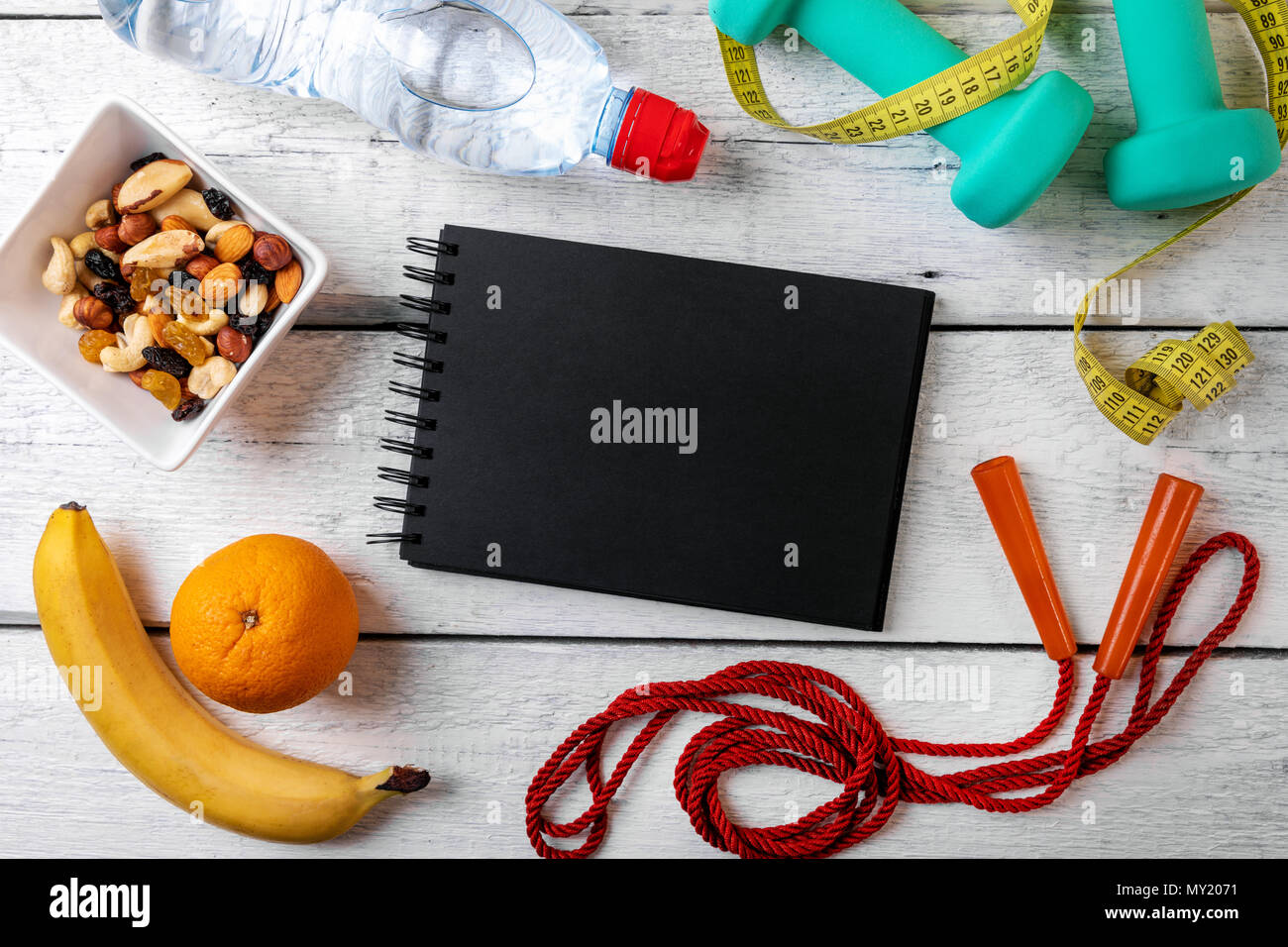 Le attrezzature per il fitness e nutrizione bianco su sfondo di legno con notebook vuoto Foto Stock