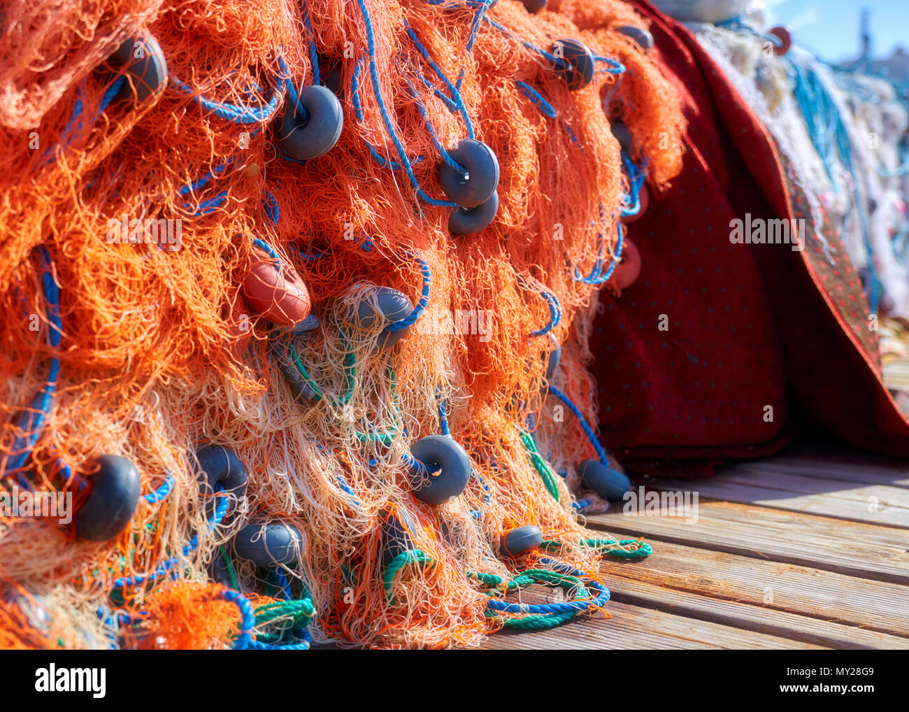 Pila di orange rete da pesca con corda blu e galleggia sul dock. Close up. Foto Stock