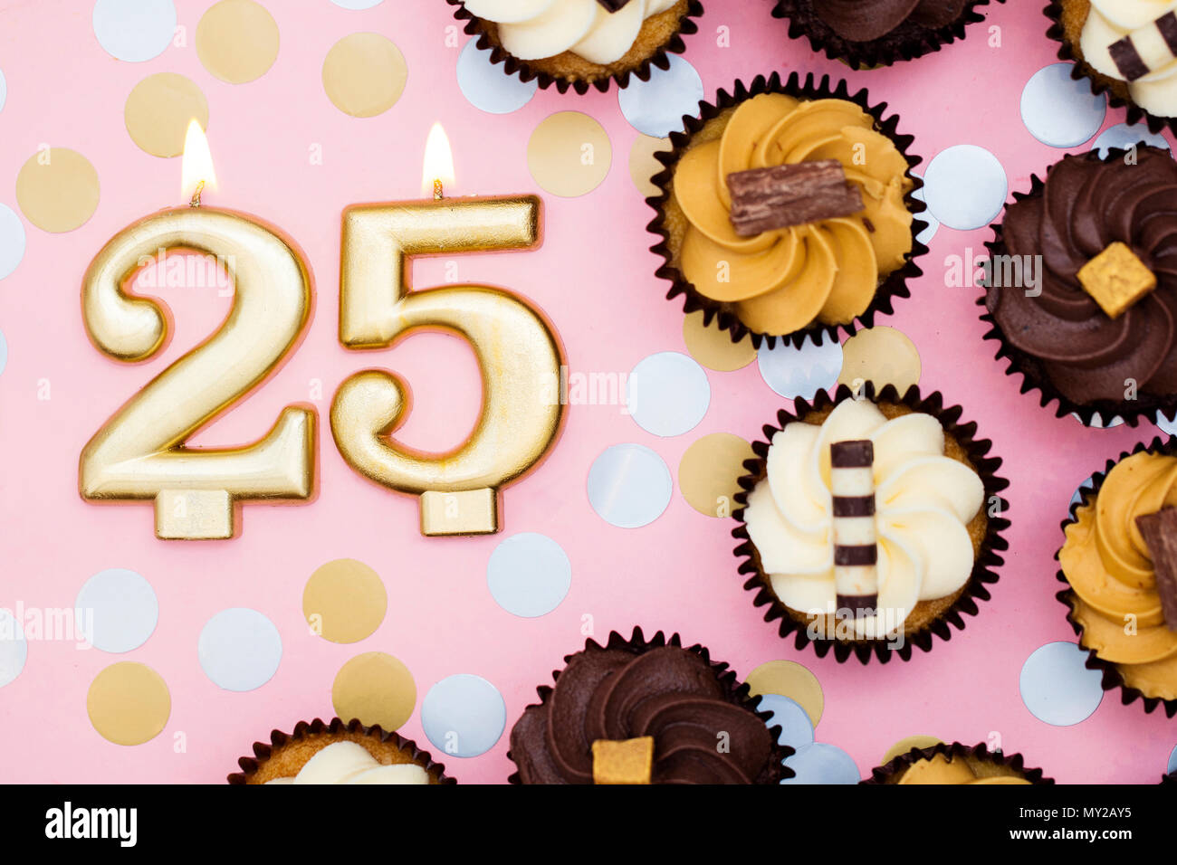 Numero 25 oro candela con tortine contro un pastello sfondo rosa Foto Stock