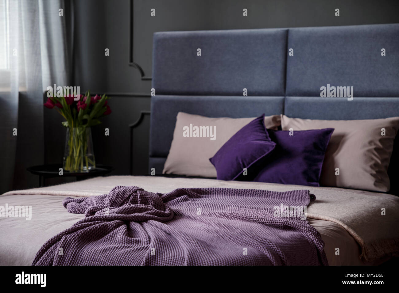 Close-up di violetta un lenzuolo sul letto in camera da letto femminile interiore con fiori Foto Stock