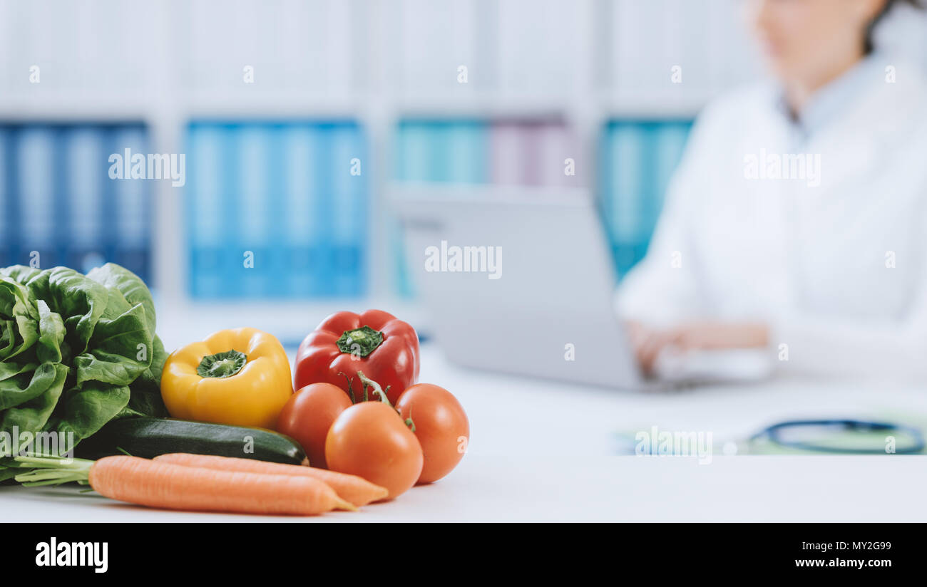 Nutrizionista professionista lavora in ufficio e sano di verdure fresche in primo piano: la dieta e il concetto di salute Foto Stock