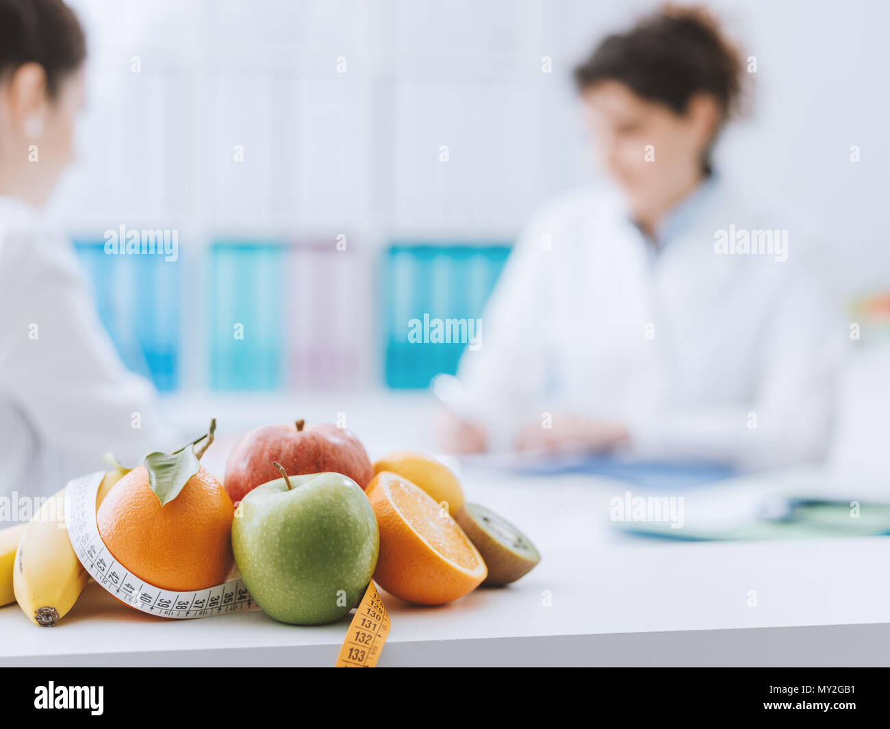Nutrizionista professionista incontro un paziente in ufficio e sani frutti con nastro di misurazione in primo piano : una sana alimentazione e dieta concetto Foto Stock