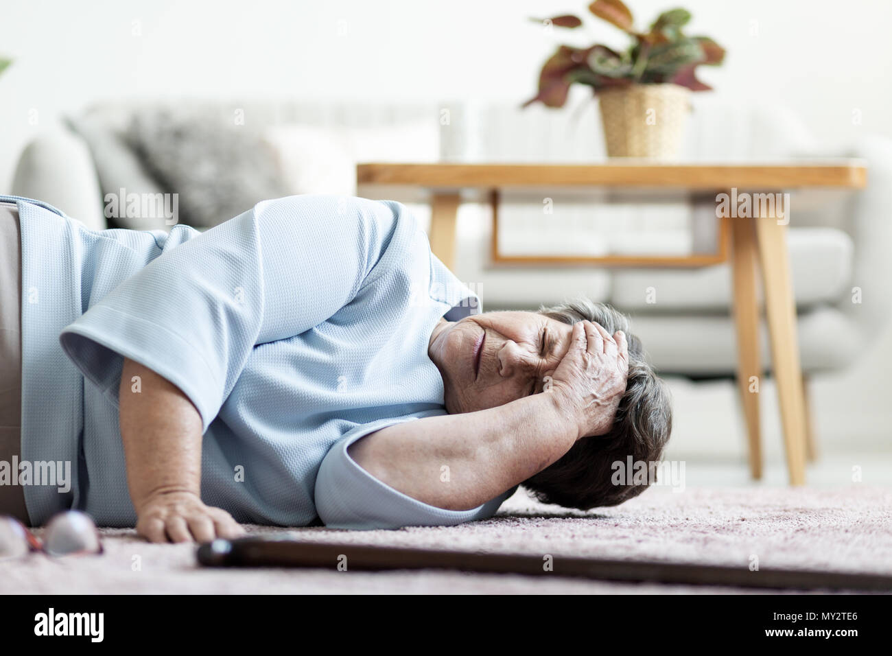 Senior donna con un mal di testa dopo la caduta verso il basso a casa Foto Stock