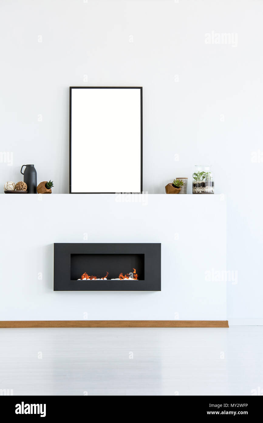 Mockup del poster vuoto nero sopra il camino in semplice bianco living room interior. Foto reale con un posto per la vostra scheda grafica Foto Stock