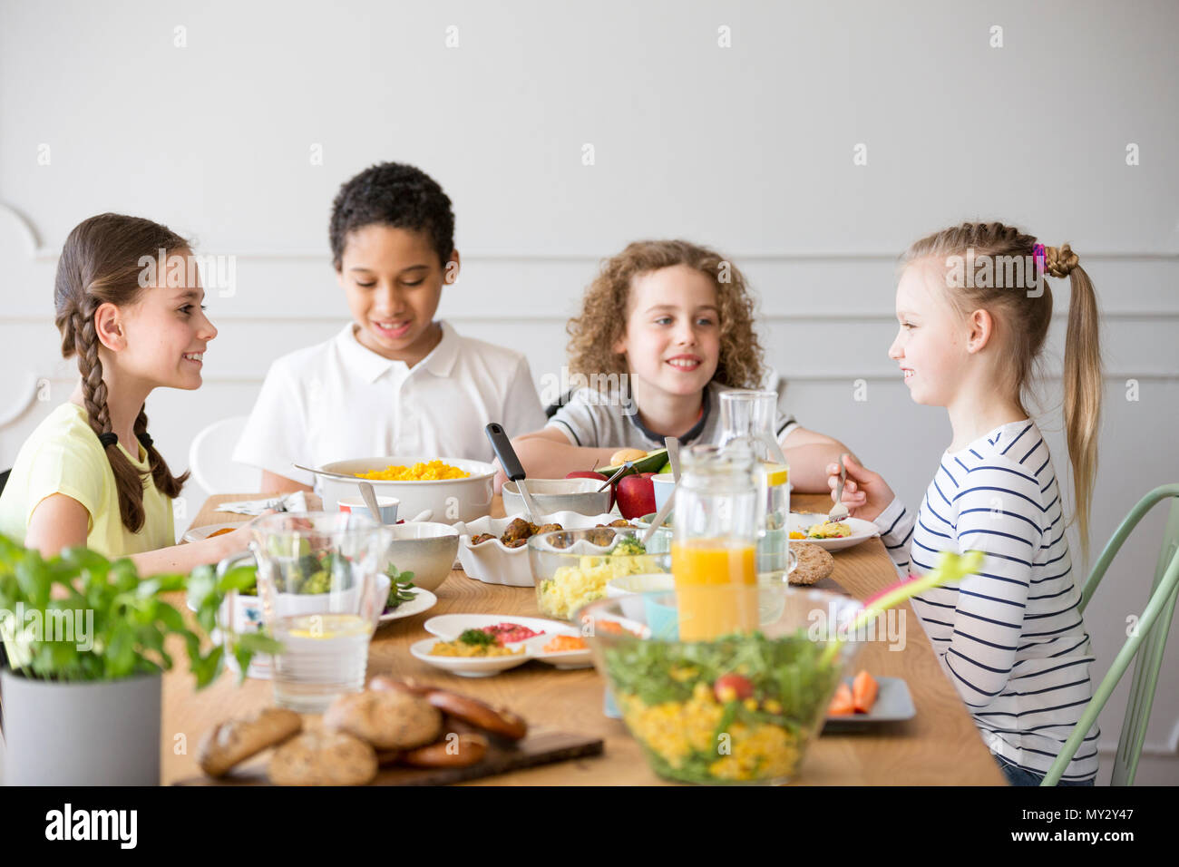 Bambini sorridenti di mangiare la cena durante la celebrazione della giornata per i bambini a casa Foto Stock