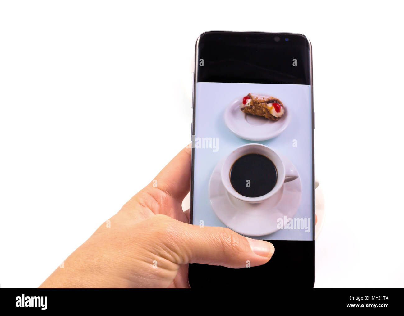 Le mani di scattare la foto, caffè e dolce cookie con uno smart phone in sfondo bianco. Foto Stock