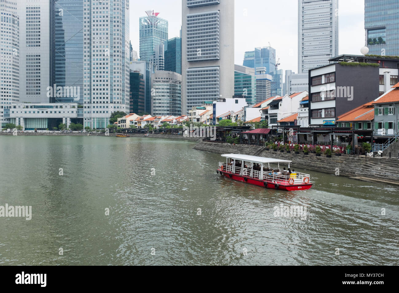Bar e ristoranti la linea la banca del fiume Singapore al Boat Quay offuscato dall alto edifici per uffici dietro di loro. Foto Stock