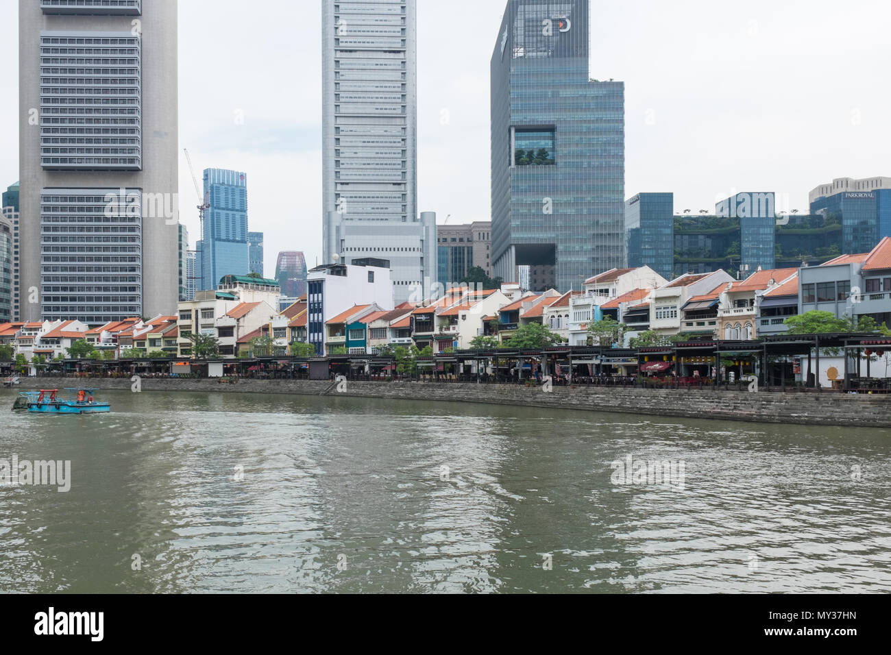Bar e ristoranti la linea la banca del fiume Singapore al Boat Quay offuscato dall alto edifici per uffici dietro di loro. Foto Stock
