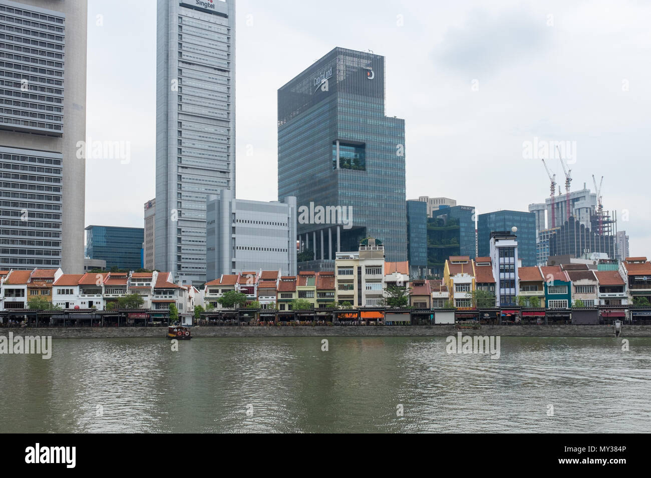 Bar e ristoranti la linea la banca del fiume Singapore al Boat Quay offuscato dall alto edifici per uffici dietro di loro. Foto Stock