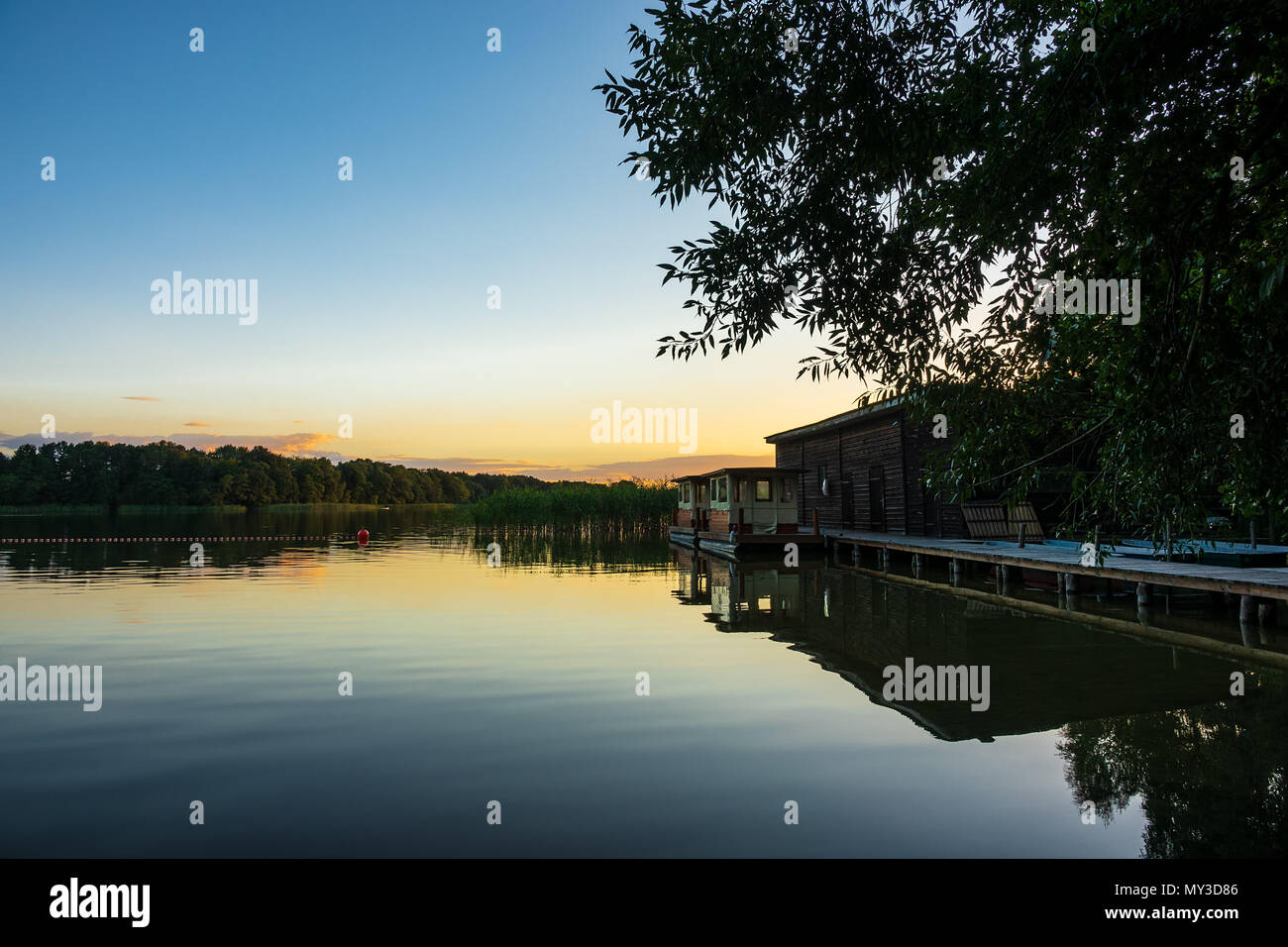 Il panorama su un lago con alberi e boatshouse. Foto Stock