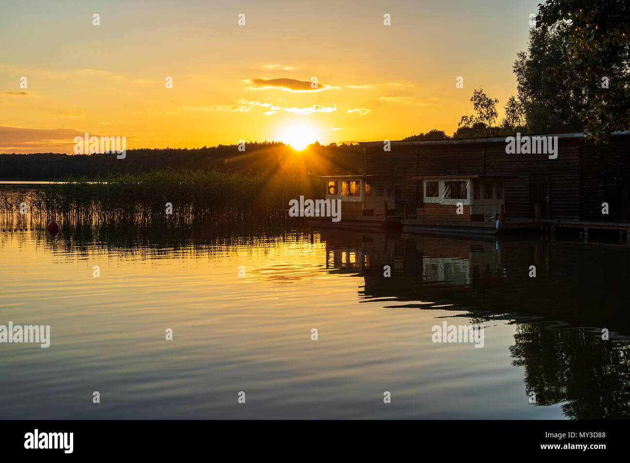 Il panorama su un lago con alberi e boatshouse. Foto Stock