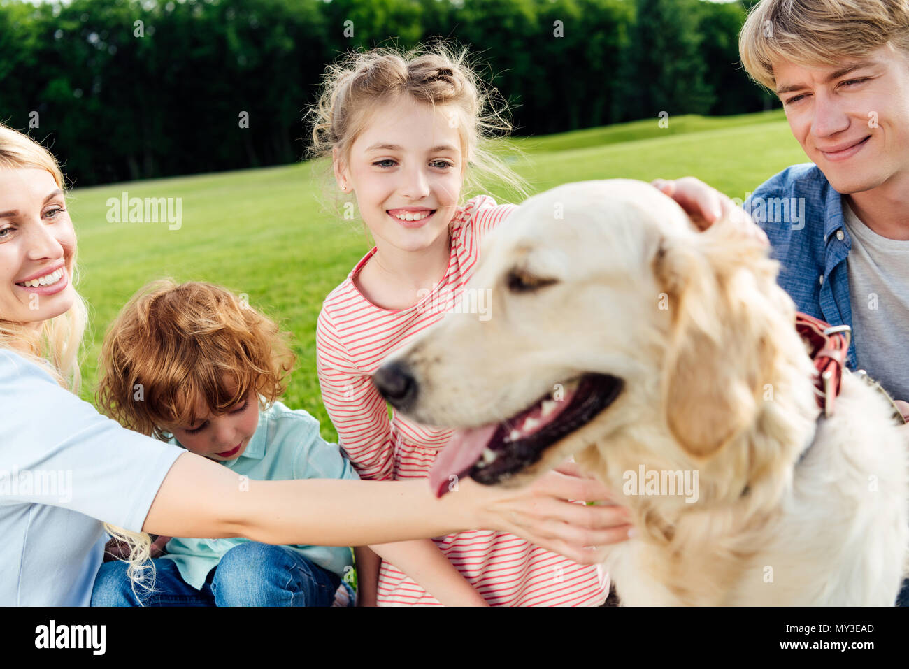 Felice famiglia con due bambini di accarezzare il cane in posizione di parcheggio Foto Stock