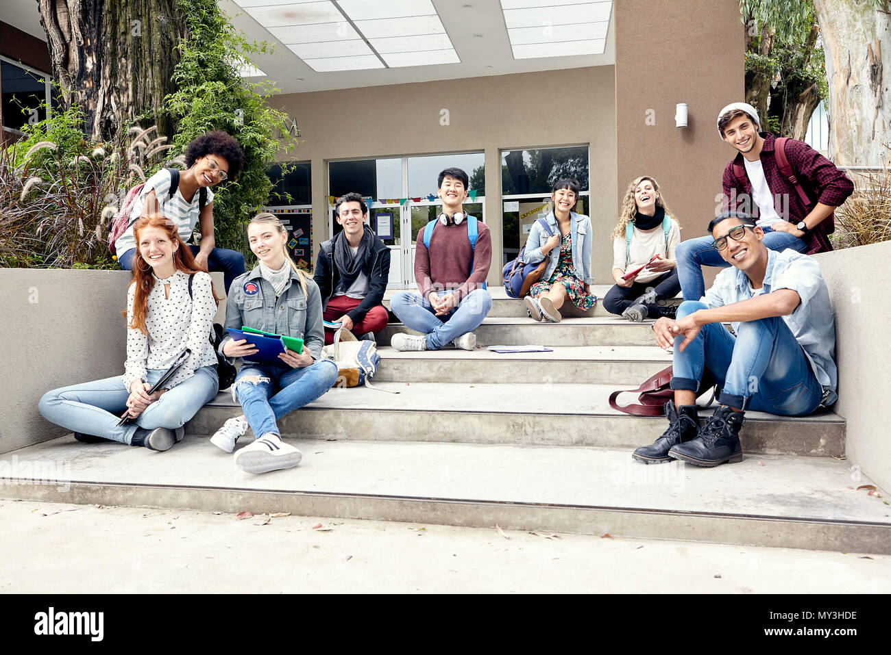 Studenti del college seduti sui gradini fuori dall'edificio, ritratto Foto Stock