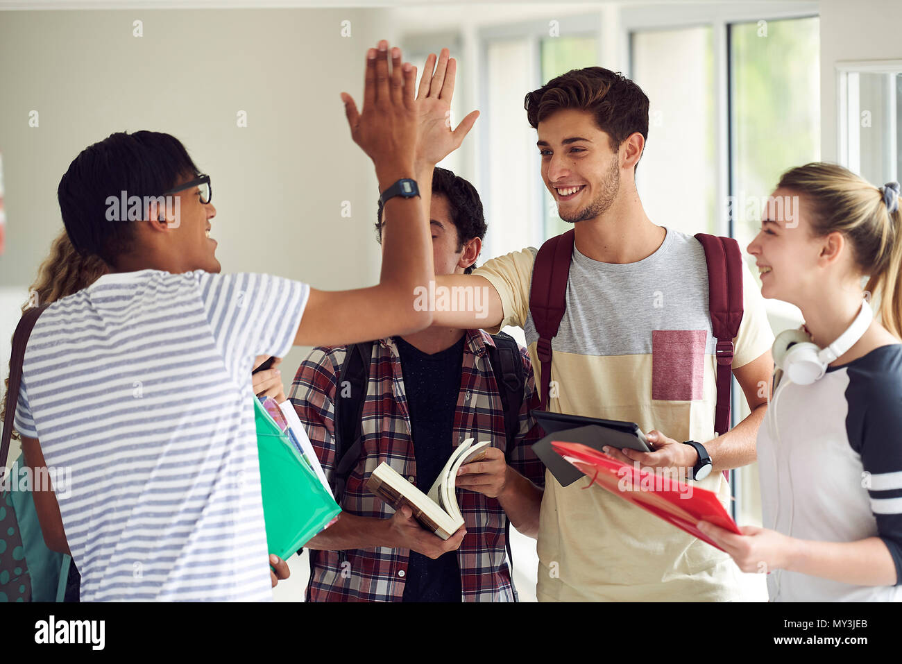 Gli studenti dando a ogni altro ad alta cinque nel corridoio Foto Stock