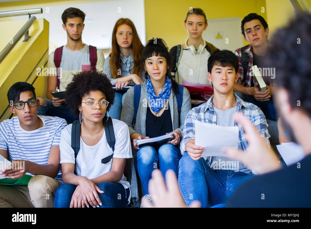 Gruppo di studenti seduti sulle scale, ascoltando la presentazione informale Foto Stock