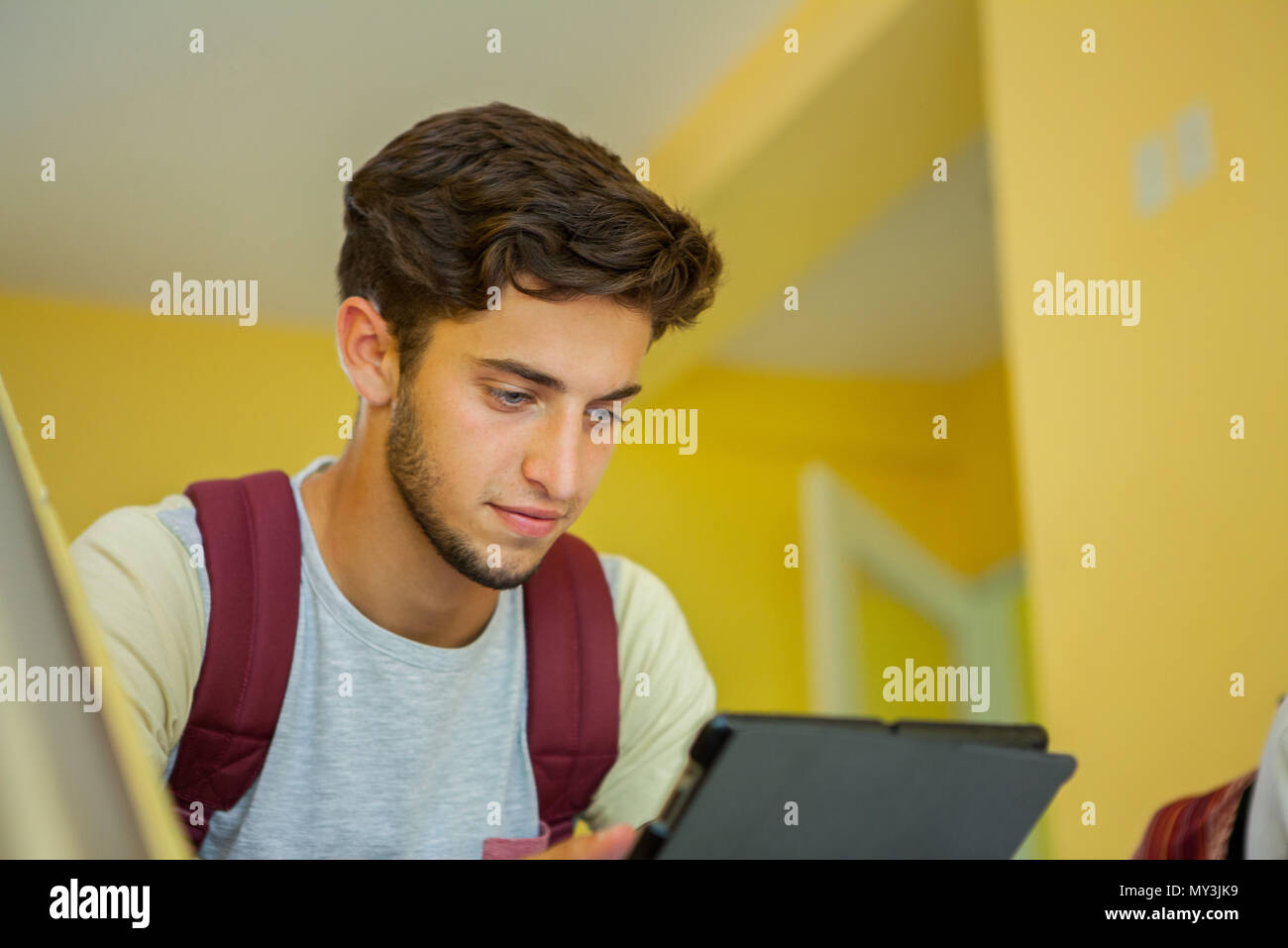 Uno studente universitario che guarda digitale compressa tra le classi Foto Stock