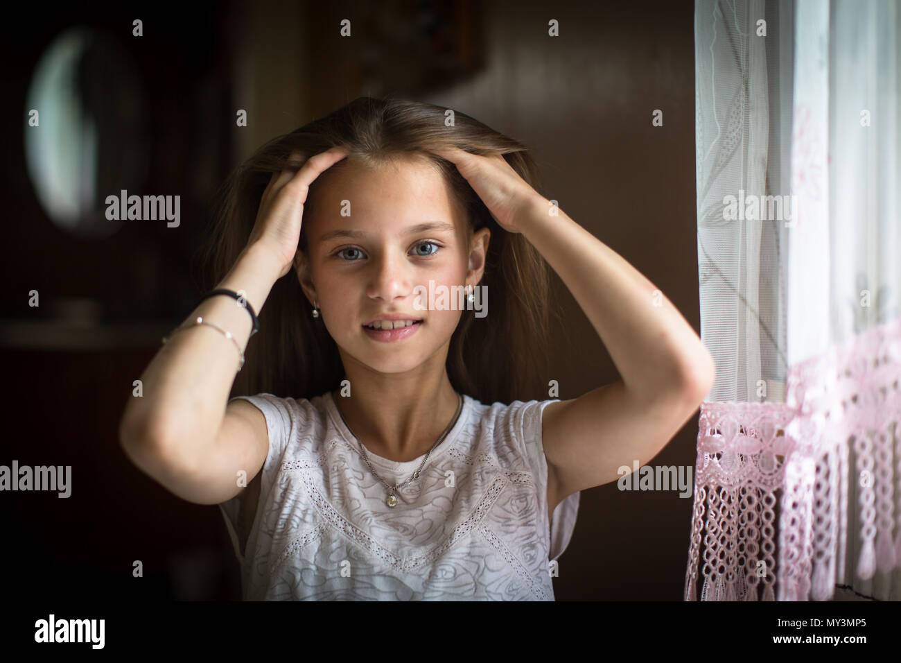 Carino dieci-anno-vecchia ragazza in posa per la telecamera seduta al tavolo. Foto Stock